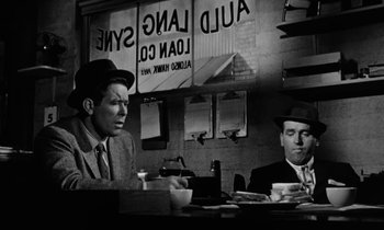 Movie still from “The Absent Minded Professor” (1961), directed by Robert Stevenson – Two men sitting at a table in front of a sign; Medium shot, Low angle