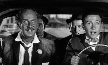 Movie still from “The Absent Minded Professor” (1961), directed by Robert Stevenson – A black and white photo of a group of men in a car; Medium shot, Low angle