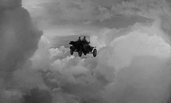 Movie still from “The Absent Minded Professor” (1961), directed by Robert Stevenson – An old car flying through the clouds with a man in the back seat; Extreme Wide shot, Overhead angle