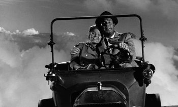 Movie still from “The Absent Minded Professor” (1961), directed by Robert Stevenson – An old photo of a man and a woman driving a car; Wide shot, High angle