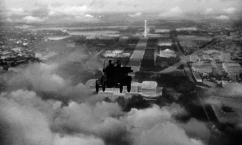 Movie still from “The Absent Minded Professor” (1961), directed by Robert Stevenson – An old car flying over a city in the clouds; Extreme Wide shot, Low angle