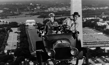 Movie still from “The Absent Minded Professor” (1961), directed by Robert Stevenson – Two men are in an old car near the washington monument; Wide shot, Low angle
