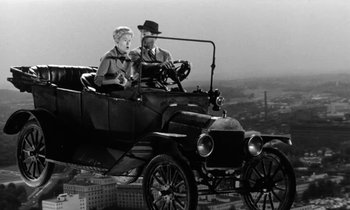 Movie still from “The Absent Minded Professor” (1961), directed by Robert Stevenson – An older couple riding in an old fashioned car; Wide shot, Low angle