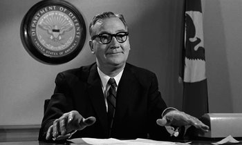 Movie still from “The Absent Minded Professor” (1961), directed by Robert Stevenson – An older man in a suit sitting at a desk; Medium shot, Low angle