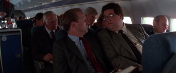 Movie still from “The Accidental Tourist” (1988), directed by Lawrence Kasdan – Two men in business suits are sitting next to each other; Medium shot, Over the shoulder angle