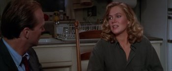 Movie still from “The Accidental Tourist” (1988), directed by Lawrence Kasdan – A woman sitting in a chair in front of a kitchen sink; Medium shot, Over the shoulder angle