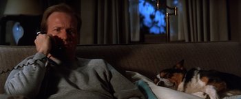 Movie still from “The Accidental Tourist” (1988), directed by Lawrence Kasdan – A man laying on a couch next to a dog; Medium shot, High angle