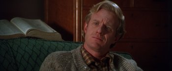 Movie still from “The Accidental Tourist” (1988), directed by Lawrence Kasdan – A person sitting on a couch wearing a sweater; Close Up shot, Over the shoulder angle