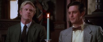Movie still from “The Accidental Tourist” (1988), directed by Lawrence Kasdan – Two men in suits are standing in front of a candle; Close Up shot, Over the shoulder angle