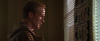 Movie still from “The Accidental Tourist” (1988), directed by Lawrence Kasdan – A man standing in front of a window looking out of the blinds; Close Up shot, Low angle