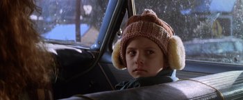 Movie still from “The Accidental Tourist” (1988), directed by Lawrence Kasdan – A young child wearing a hat sitting in the back of a car; Close Up shot, Over the shoulder angle