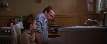 Movie still from “The Accidental Tourist” (1988), directed by Lawrence Kasdan – A man and a little girl looking at a toilet; Medium shot, Low angle
