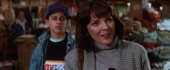 Movie still from “The Accidental Tourist” (1988), directed by Lawrence Kasdan – A woman and a young boy are in a store together; Close Up shot, Over the shoulder angle