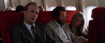 Movie still from “The Accidental Tourist” (1988), directed by Lawrence Kasdan – Two men and a woman sitting on a plane; Close Up shot, Low angle