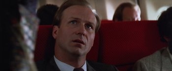 Movie still from “The Accidental Tourist” (1988), directed by Lawrence Kasdan – A man in a suit and tie sitting on a train; Close Up shot, Low angle