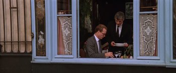 Movie still from “The Accidental Tourist” (1988), directed by Lawrence Kasdan – Two men in business suits sitting at a table; Wide shot, High angle