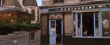 Movie still from “The Accidental Tourist” (1988), directed by Lawrence Kasdan – A woman walking in front of a restaurant; Extreme Wide shot, High angle
