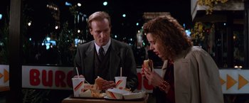 Movie still from “The Accidental Tourist” (1988), directed by Lawrence Kasdan – A man and a woman sitting at a table eating a sandwich; Medium shot, Over the shoulder angle