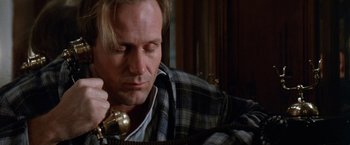 Movie still from “The Accidental Tourist” (1988), directed by Lawrence Kasdan – A man is talking on a phone while sitting on a couch; Close Up shot, Low angle