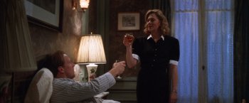 Movie still from “The Accidental Tourist” (1988), directed by Lawrence Kasdan – A woman holding a wine glass in front of a man; Medium shot, Over the shoulder angle