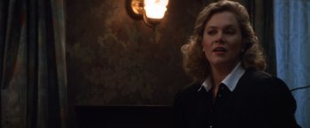 Movie still from “The Accidental Tourist” (1988), directed by Lawrence Kasdan – A woman standing in front of a lamp in a room; Close Up shot, Over the shoulder angle