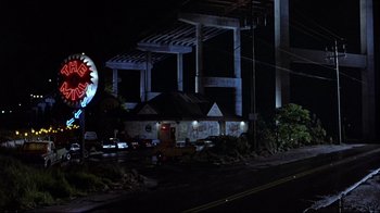 Movie still from “The Accused” (1988), directed by Jonathan Kaplan – A night time view of a building with a sign on the side of the building; Extreme Wide shot, Low angle
