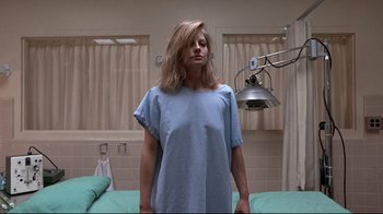 Movie still from “The Accused” (1988), directed by Jonathan Kaplan – A woman standing in a hospital room wearing a blue gown; Medium shot, Low angle