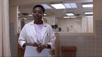 Movie still from “The Accused” (1988), directed by Jonathan Kaplan – A woman in a white lab coat holding a binder; Medium shot, Low angle