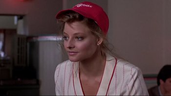 Movie still from “The Accused” (1988), directed by Jonathan Kaplan – A woman wearing a baseball cap and a white robe; Close Up shot, Over the shoulder angle