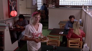 Movie still from “The Accused” (1988), directed by Jonathan Kaplan – A woman holding a plate of food in a restaurant; Medium shot, Over the shoulder angle