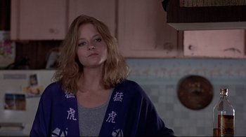 Movie still from “The Accused” (1988), directed by Jonathan Kaplan – A woman with long blonde hair standing in a kitchen; Close Up shot, Over the shoulder angle