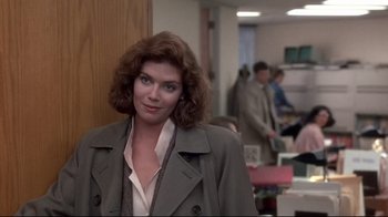 Movie still from “The Accused” (1988), directed by Jonathan Kaplan – A woman in a trench coat standing in a room; Medium shot, Over the shoulder angle