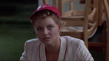 Movie still from “The Accused” (1988), directed by Jonathan Kaplan – A woman wearing a baseball cap and a white jacket; Close Up shot, Over the shoulder angle