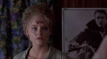 Movie still from “The Accused” (1988), directed by Jonathan Kaplan – A young woman with makeup and a scar on her forehead; Close Up shot, Over the shoulder angle