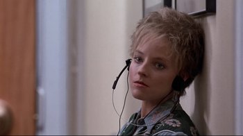 Movie still from “The Accused” (1988), directed by Jonathan Kaplan – A person with a microphone in a room; Close Up shot, High angle