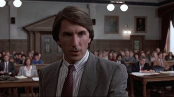Movie still from “The Accused” (1988), directed by Jonathan Kaplan – A man wearing a suit and tie in front of a group of people; Close Up shot, Low angle
