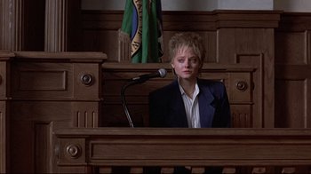 Movie still from “The Accused” (1988), directed by Jonathan Kaplan – A woman in a court room with a microphone; Medium shot, Low angle