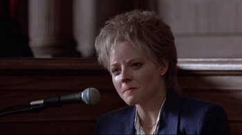 Movie still from “The Accused” (1988), directed by Jonathan Kaplan – A woman in a blue jacket is sitting in front of a microphone; Close Up shot, Low angle