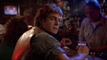 Movie still from “The Accused” (1988), directed by Jonathan Kaplan – A man sitting at a table in front of a glass of wine; Close Up shot, Over the shoulder angle