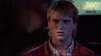 Movie still from “The Accused” (1988), directed by Jonathan Kaplan – A young man in a red leather jacket looks into the camera; Close Up shot, Over the shoulder angle