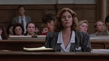 Movie still from “The Accused” (1988), directed by Jonathan Kaplan – A woman sitting in front of other people in a courtroom; Medium shot, Low angle