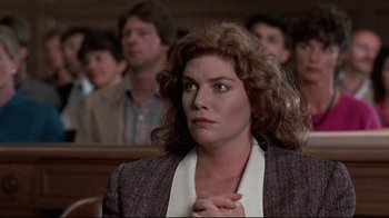 Movie still from “The Accused” (1988), directed by Jonathan Kaplan – A woman with curly hair is standing in front of a group of people in a court room; Close Up shot, Low angle