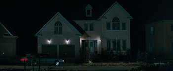Movie still from “The Adjuster” (1991), directed by Atom Egoyan – A car parked in front of a house at night; Extreme Wide shot, Low angle