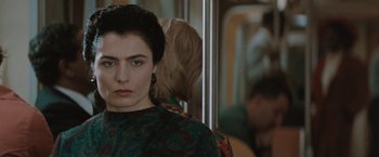 Movie still from “The Adjuster” (1991), directed by Atom Egoyan – A woman in a green dress on a train; Close Up shot, Over the shoulder angle