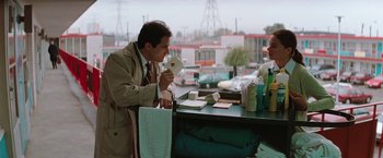 Movie still from “The Adjuster” (1991), directed by Atom Egoyan – A man in a tan jacket is eating a sandwich; Medium shot, Over the shoulder angle