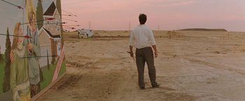 Movie still from “The Adjuster” (1991), directed by Atom Egoyan – A man standing in the middle of an empty field; Extreme Wide shot, Low angle