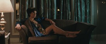 Movie still from “The Adjuster” (1991), directed by Atom Egoyan – A woman sitting on top of a couch in a living room; Medium shot, High angle
