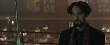 Movie still from “The Adjuster” (1991), directed by Atom Egoyan – A man in a suit and tie in front of a window; Close Up shot, Over the shoulder angle