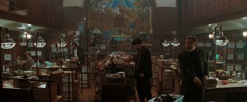 Movie still from “The Adjuster” (1991), directed by Atom Egoyan – A group of people in a room with tables and chairs; Wide shot, High angle