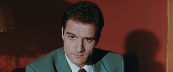 Movie still from “The Adjuster” (1991), directed by Atom Egoyan – A person wearing a suit and tie; Close Up shot, Low angle